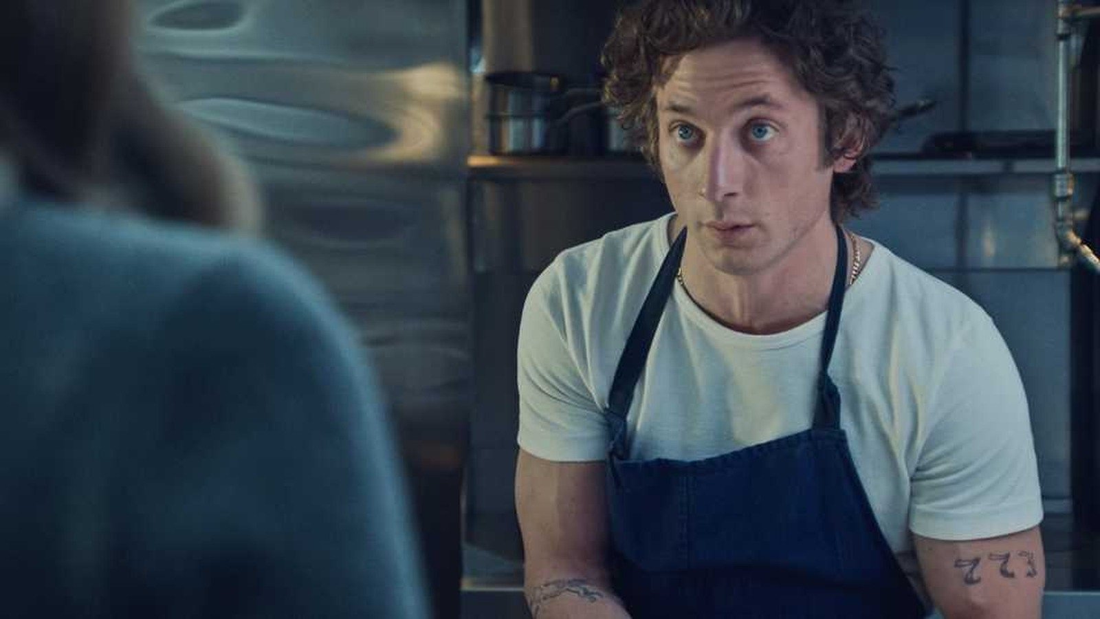 The Bear still featuring Jeremy Allen White as Carmy Berzatto in his blue apron and white t shirt